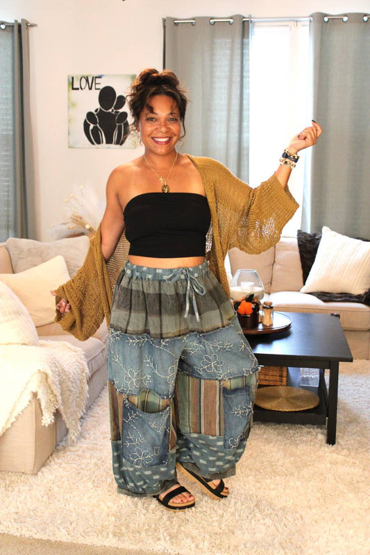 Woman wearing a black top, gold toned cardigan, and blue patchwork pants.