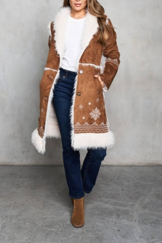 Woman wearing a brown shearling coat with white fur trim and white embroidery accent details.
