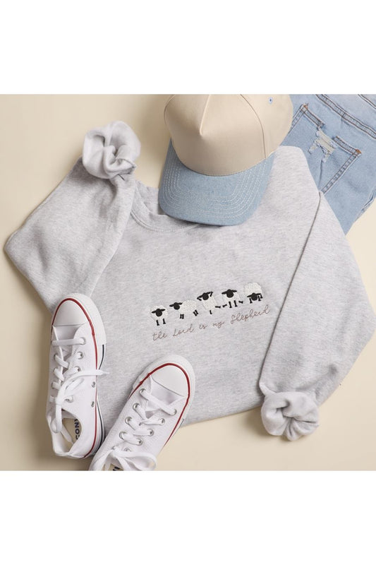 Light gray sweatshirt with multiple cute embroidered sheep and the message "The lord is my Shepard" in a brown cursive font.