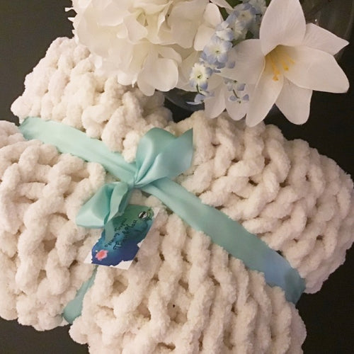 Blanket tied with light cyan bow in gift shape with tag hanging from it.