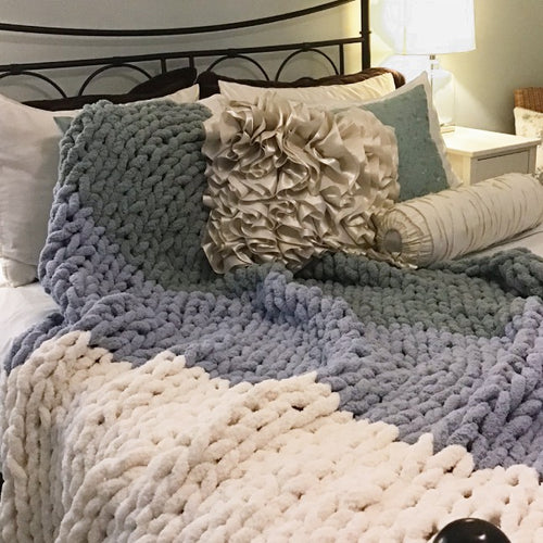 Cream, blue, & sage green ombre blanket laid on bed.