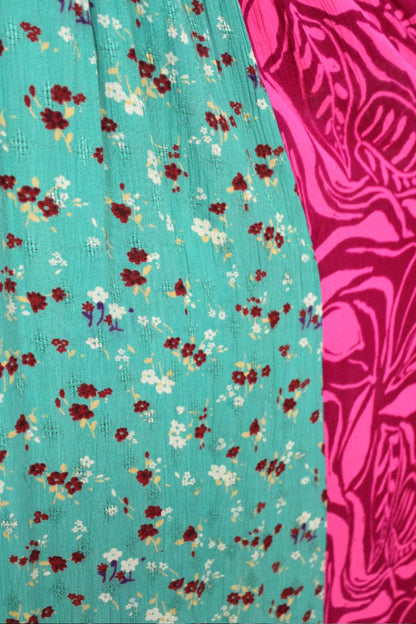 Close-up of teal fabric with floral pattern and pink fabric with abstract design.