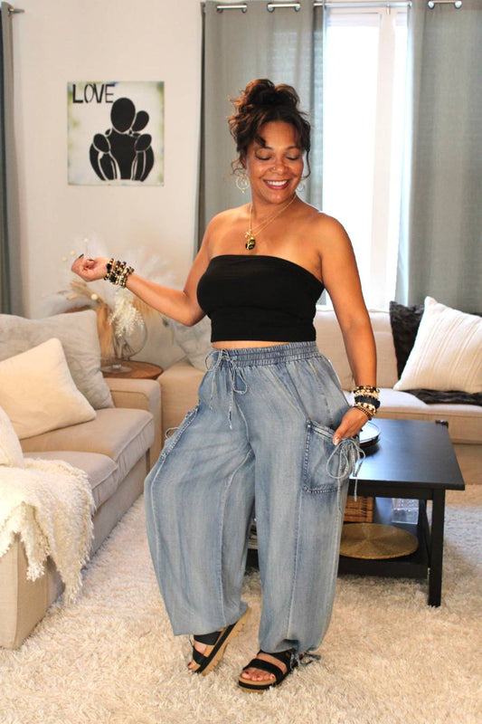 Model wearing a black tube top and light blue flowy denim pants.