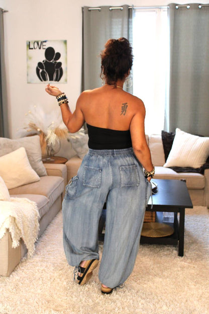 Model showing the back of a black tube top and light blue flowy denim pants.