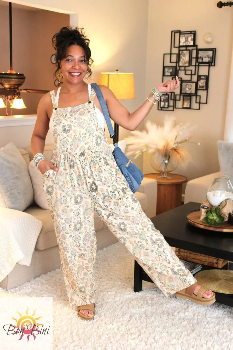 Model wearing a cream floral overalls with adjustable straps and a large front chest pocket.