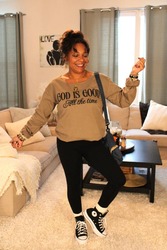 Model wearing a 'God is Good All the time' brown sweatshirt, black leggings, and recycled denim crossbody bag.