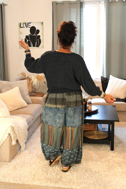 Woman in a living room wearing a dark gray sweater and blue patterned pants. Back view.