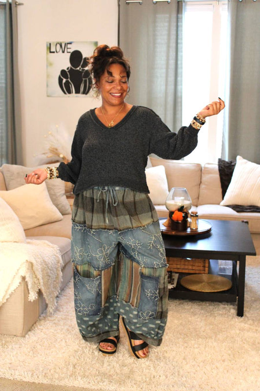 Woman in a living room wearing a dark gray sweater and blue patterned pants.