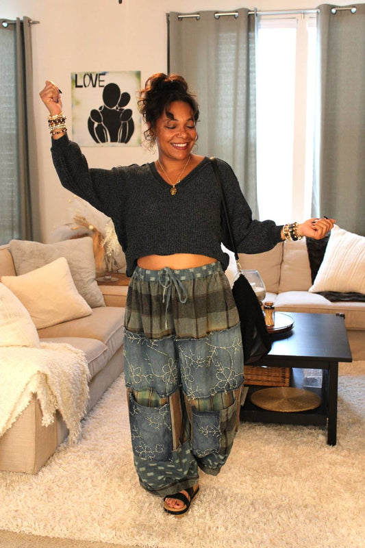 Woman in a living room wearing a dark gray sweater and blue patterned pants.