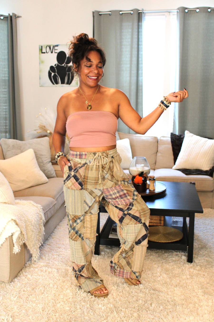 Model posing in a pink bamboo tube top and light toned plaid pants featuring an x pattern similar to railroad crossings.