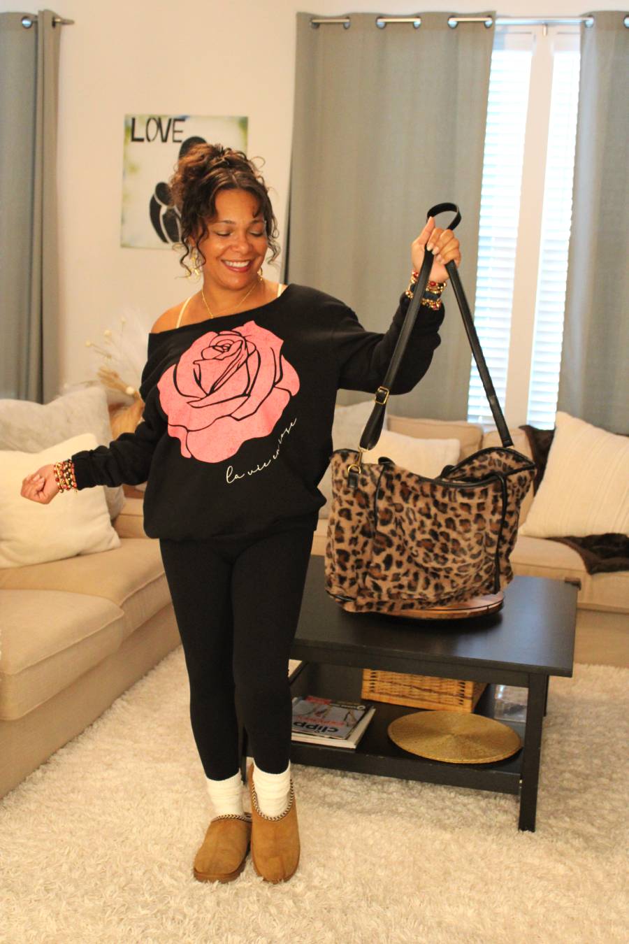 Model with a leopard print bag, black sweater with pink rose design.