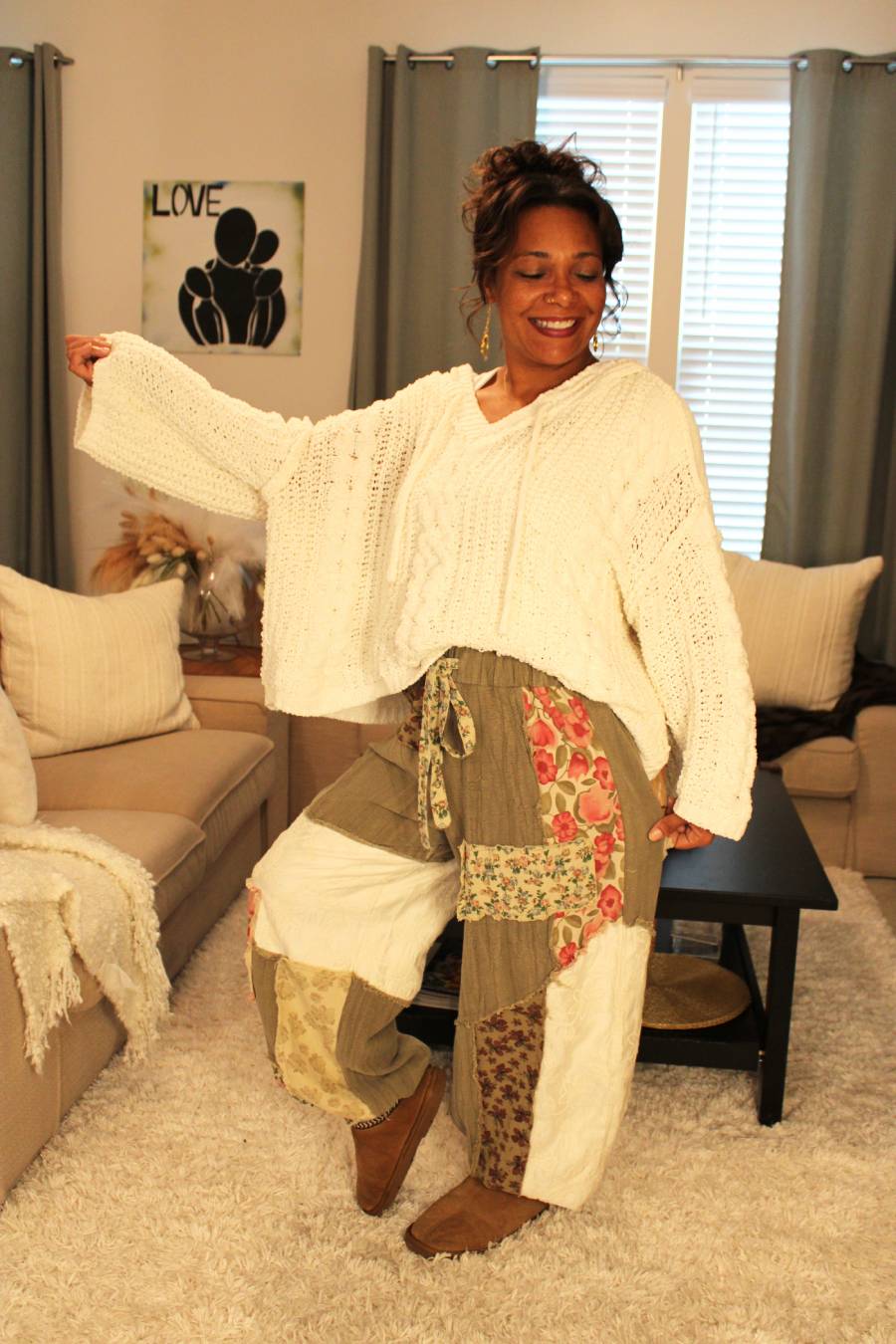 Woman wearing a white knit texture hoodie sweater and patterned pants.