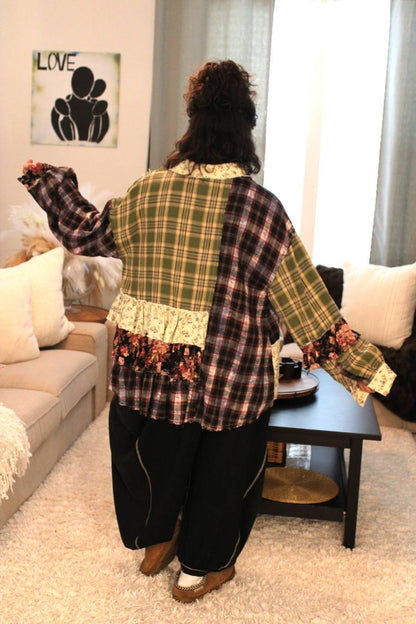 Model wearing a green/pink multi-color plaid shirt with it open to reveal a pink mauve tube top. Also wearing black jogger style pants with dark gray line accents. Back view.
