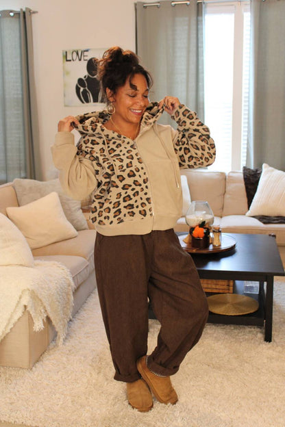 Woman wearing a beige leopard print hoodie and chocolate brown pants.
