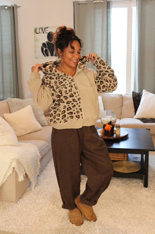 Woman wearing a beige leopard print hoodie and chocolate brown pants.