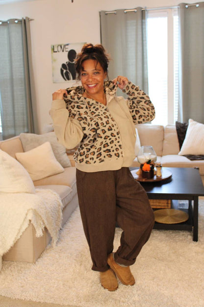 Woman showcasing the hood part of the beige/leopard print hoodie.