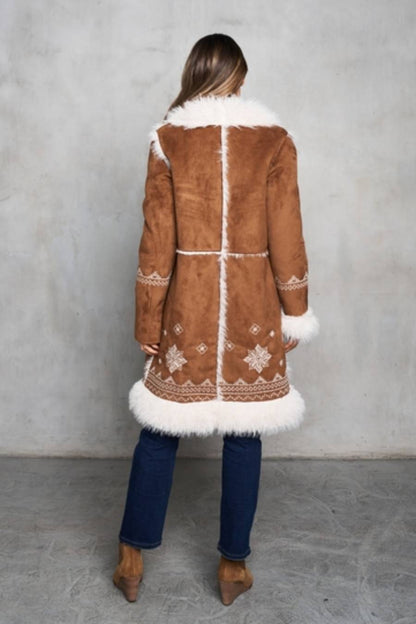 Woman wearing a brown shearling coat with white fur trim. Back view showcasing white trim line on the back.