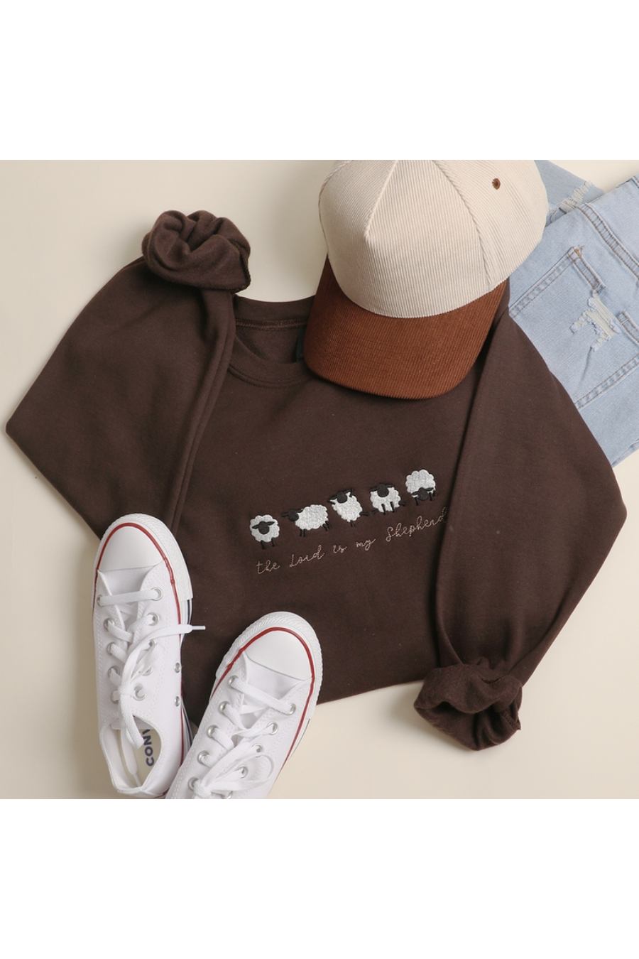 Dark brown sweatshirt with multiple cute embroidered sheep and the message "The lord is my Shepard" in a brown cursive font.