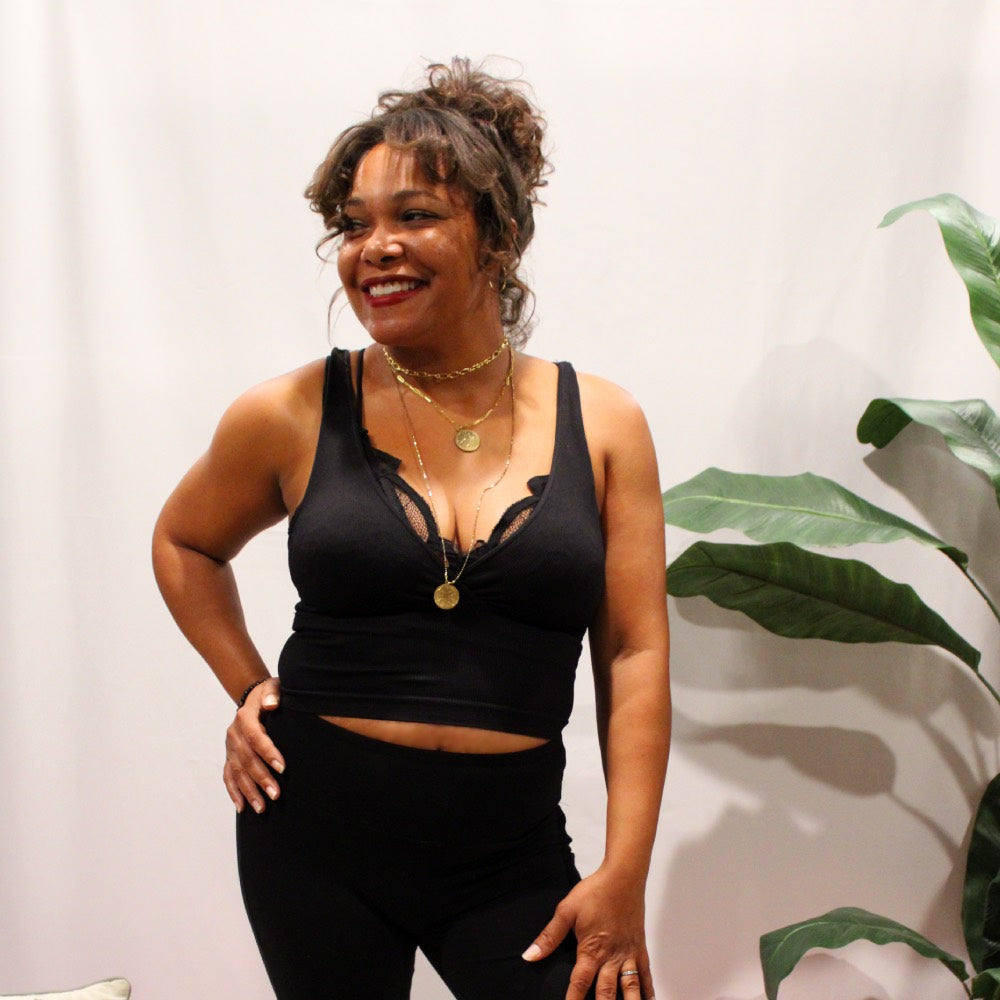 front view of black surpliced ribbed crop top with black flared yoga pants and layered necklaces